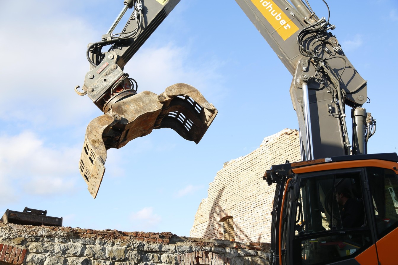 Bagger mit Abbruchgreifer bei professionellen Abriss- und Rückbauarbeiten auf einer Baustelle.