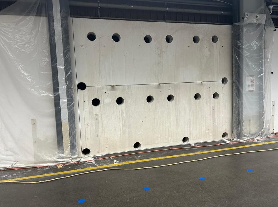 Mehrere präzise Kernbohrungen in einer Betonwand innerhalb einer Industriehalle.
