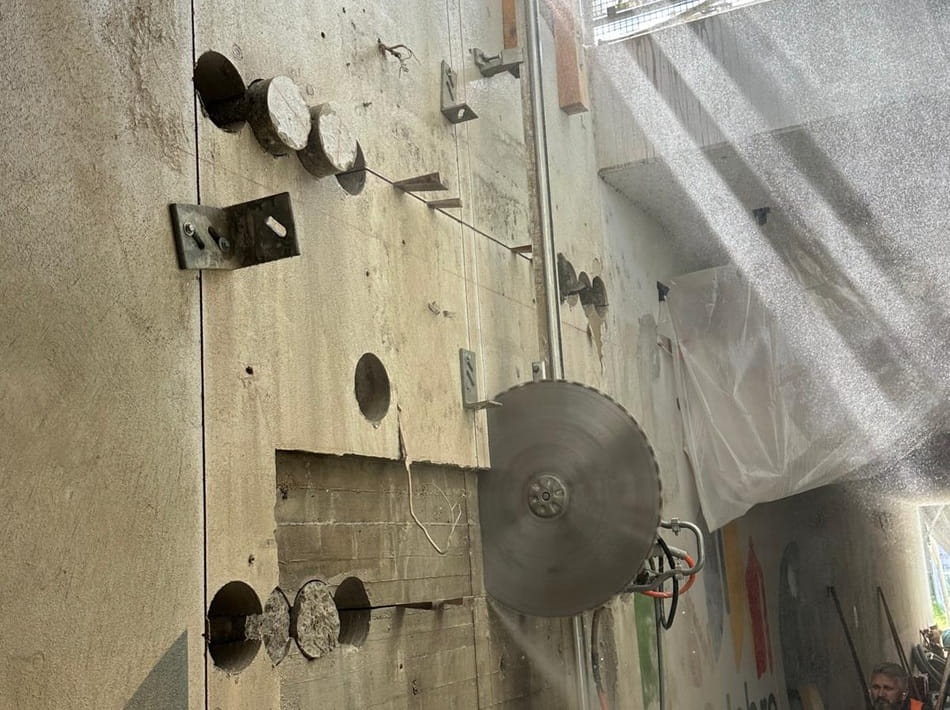 Wandsägearbeiten an einer massiven Betonwand mit Kernbohrungen und schienengeführter Betonsäge.