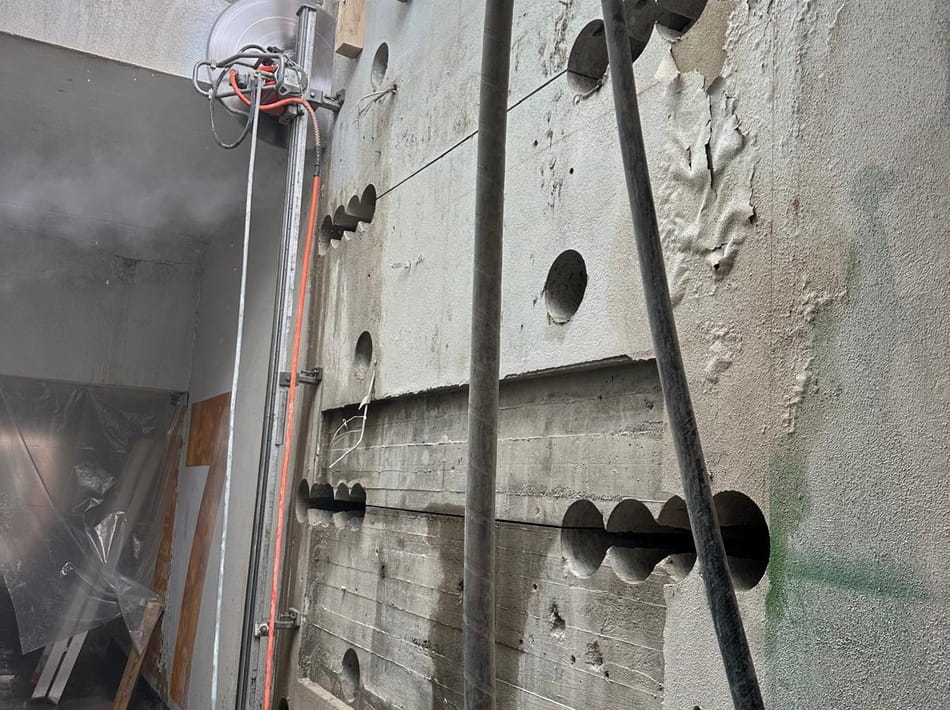 Vorbereitete Betonwand mit Kernbohrungen und Wandsäge für einen großflächigen Wanddurchbruch.